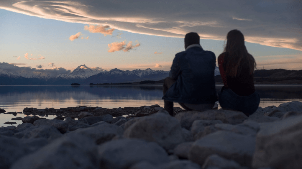Photo of two people overlooking a lake in new zealand at sunset for a post on overcoming travel burnout